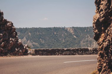 Sarmal yol, parlak güneş ışığı altında sakin bir kaçışta kayalık dağ manzarasını kucaklıyor.