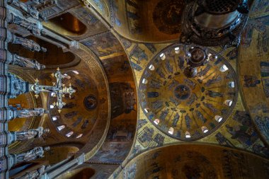 Altın mozaikler ve karmaşık freskler, yumuşak doğal ışık altında dini sanat ve mermer sütunların sergilendiği tarihi bir bazilikanın içini süslüyor..