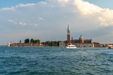 İtalya 'nın Venedik kentindeki San Giorgio Maggiore Adası' nın manzarası, ikonik kilise ve çan kulesi, yelkenli tekneleri ve parlak günbatımı gökyüzü altında sakin sularla çevrili..