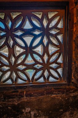 İtalya, Venedik 'teki İç Çekmeler Köprüsü' nün içinde karmaşık bir taş kafes penceresi. Manzara, Venedik 'in ikonik su yolları ve mimarisini gösteren başka bir köprünün altındaki kanalı gözler önüne seriyor..