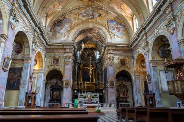 Freskli tavanlar, karmaşık kemerler, bir haç süsü ve dekoratif mimari detaylar içeren zengin dekore edilmiş bir kilise iç mimarisi..