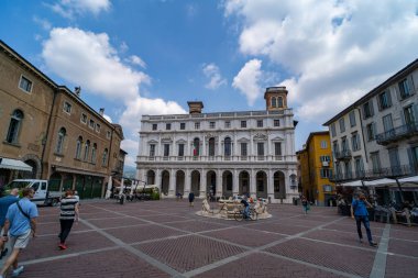Bergamo 'daki Piazza Vecchia' nın manzarasında Contarini Çeşmesi ve parlak gökyüzü altında dağınık bulutlar var..