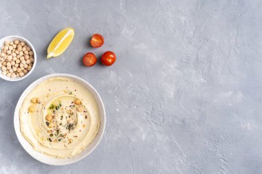 Gri seramik tabakta zeytinyağlı humus. Atıştırmalık ekmek ve tost çubukları. Gri arkaplandaki üst manzara. Yüksek kalite fotoğraf