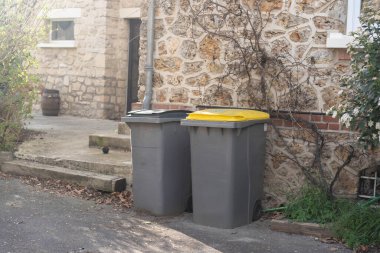 Çöp bidonları taş duvarın yanına dizilmişti. Yüksek kalite fotoğraf