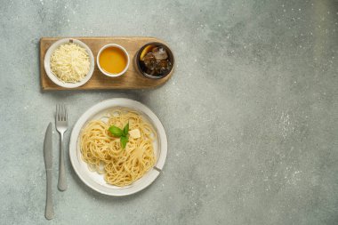 Soslu makarna kasesi, gri yüzeyde peynir ve salata. Yüksek kalite fotoğraf