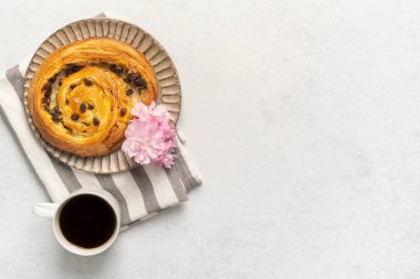Çizgili peçetede kahve ve pembe çiçeklerle lezzetli kuru üzümlü pasta. Yüksek kalite fotoğraf