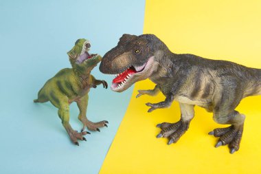 Ukrayna bayrağı metaforu gibi sarı ve mavi arka planda savaşan iki dinozor. Asgari natürmort ve renkli fotoğrafçılık