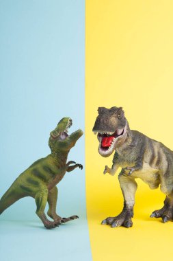 Ukrayna bayrağı metaforu gibi sarı ve mavi arka planda savaşan iki dinozor. Asgari natürmort ve renkli fotoğrafçılık