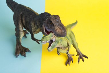 Ukrayna bayrağı metaforu gibi sarı ve mavi arka planda savaşan iki dinozor. Asgari natürmort ve renkli fotoğrafçılık