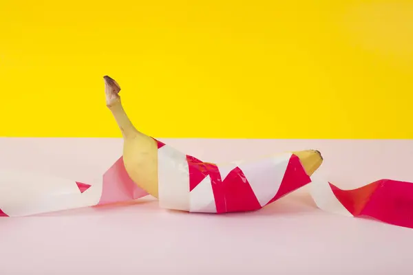 Uma Banana Madura Envolta Numa Fita Plástico Vermelha Branca Mantida — Fotografia de Stock