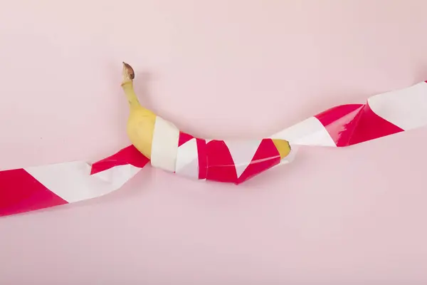 Uma Banana Madura Envolta Numa Fita Plástico Vermelha Branca Mantida — Fotografia de Stock
