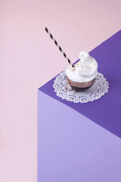 3D光学錯覚を作成するために色紙で作られたバイオレットキューブ 上にはホイップクリームとホワイトレースのドリームにスピンクコーヒーのヴィンテージピンクカップがあります 鮮やかな色と最小限のポップアート写真 ストック写真