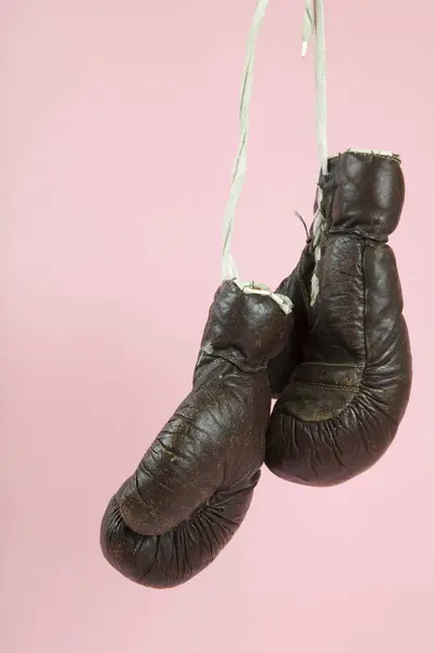 古いボクシングの手袋が キャンディピンクの背景の前に掛けられています ミニマルカラーとキレイカラーはまだライフフォト ストックフォト