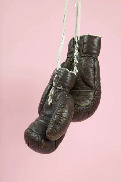 古いボクシングの手袋が キャンディピンクの背景の前に掛けられています ミニマルカラーとキレイカラーはまだライフフォト ロイヤリティフリーのストック画像
