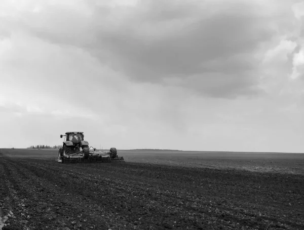 オープン田園の自然の黒い土壌のトラクターによって耕された畑 耕された畑のトラクター おいしい野菜を育てる土 きれいな暗い空の下の有機耕された畑はトラクターのための自然な土です — ストック写真