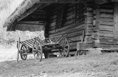 Photo on theme of old wooden hut without windows in abandoned village with cart for horse