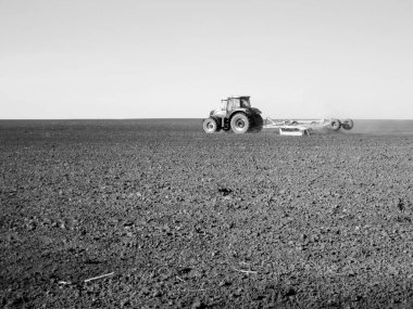 Kara toprakta traktörle sürülmüş tarla açık arazide traktör tarlada traktör, toprakta yetişen lezzetli sebzeler temiz karanlık gökyüzünün altında organik tarlalar traktör için doğal topraktır.