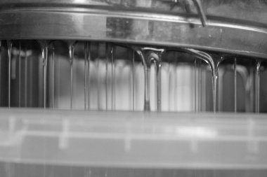 Altın nektarla doldurulmuş altıgen bal peteklerinden bir damla bal damlıyor. Bal peteği yaz kompozisyonu. Doğal bal damlası, balmumu çerçeveli arı damlası. Bal damlası bal damlatıyor bal peteğine.