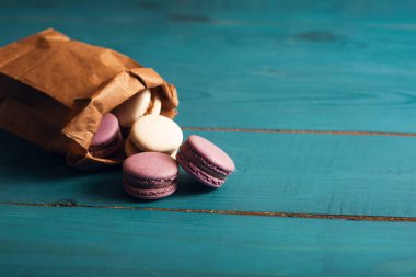 Mavi ahşap yüzeydeki kağıtta lezzetli badem kurabiyeleri var. Klasik, romantik tarzda. Ön görünüm