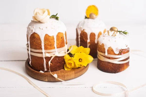 stock image Easter cakes with a delicate, light, modern design nd eggs on a white wooden background with yellow daffodils. Easter concept. Easter traditional food. Easter symbol