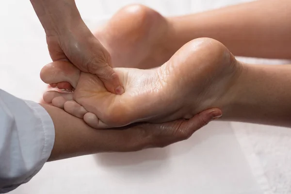Masseur doing foot massage with oil in spa salon. Spa procedures. relaxing, wellness foot massage. Body care concept. Close-up view. Female foot close-up