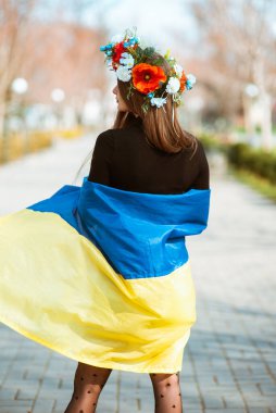 Ukrayna bayrağına sarılmış genç bir kadın başında çiçeklerle dikiliyordu. Vatanseverlik kavramı. Ukraynalı. Gönüllü olmak, sadaka vermek, minnettarlık sembolü.