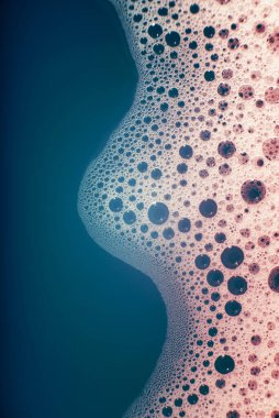 Su yüzeyinde köpüren kalın sabun köpükleri bir dalga şeklinde. Güzel parlak, modaya uygun renkler, maviden kırmızıya değişim. Makro. Sabun köpüğü dokusu, köpük.