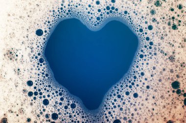Kalın köpüklü sabun köpükleri suyun yüzeyinde kalp şeklinde. Güzel parlak, modaya uygun renkler, maviden kırmızıya değişim. Makro. Sabun köpüğü dokusu, köpük.