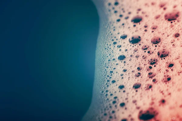 Su yüzeyinde köpüren kalın sabun köpükleri. Güzel parlak, modaya uygun renkler, maviden kırmızıya değişim. Makro. Sabun köpüğü dokusu, köpük.