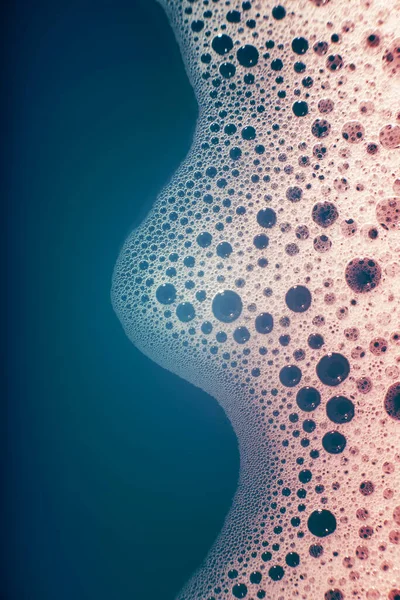 Su yüzeyinde köpüren kalın sabun köpükleri bir dalga şeklinde. Güzel parlak, modaya uygun renkler, maviden kırmızıya değişim. Makro. Sabun köpüğü dokusu, köpük.