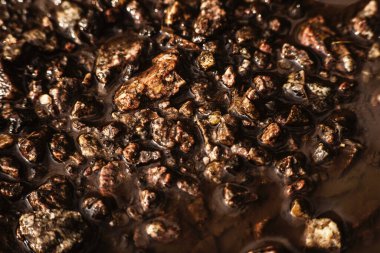 Su birikintisindeki küçük taşların dokusu, güneş ışığı, eski harap olmuş asfalt. Arka plan çok detaylı. Yağmurdan sonra granit taşlar