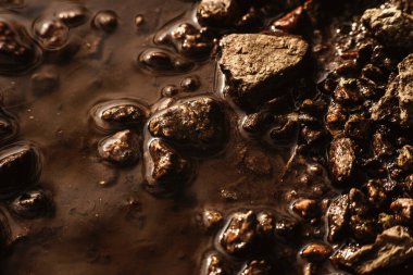 Su birikintisindeki küçük taşların dokusu, güneş ışığı, eski harap olmuş asfalt. Arka plan çok detaylı. Yağmurdan sonra granit taşlar