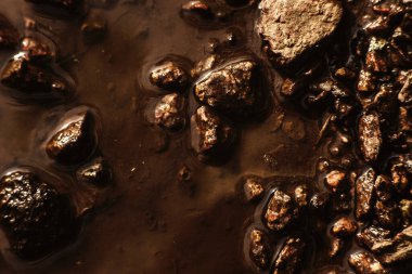 Su birikintisindeki küçük taşların dokusu, güneş ışığı, eski harap olmuş asfalt. Arka plan çok detaylı. Yağmurdan sonra granit taşlar