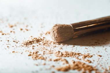 Parçalanmış makyaj tozu çıplak bir tonda ve beyaz arka planda büyük bir toz fırçası ile. Macro, yakın plan. Boşluğu kopyala, metin için yer, Kozmetik kavramı