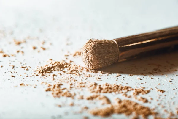 Parçalanmış makyaj tozu çıplak bir tonda ve beyaz arka planda büyük bir toz fırçası ile. Macro, yakın plan. Boşluğu kopyala, metin için yer, Kozmetik kavramı
