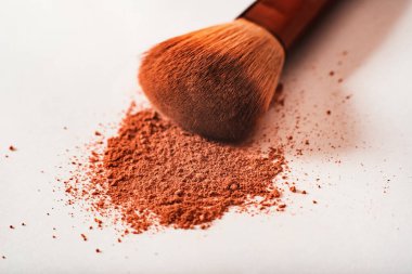 Parçalanmış makyaj tozu çıplak bir tonda ve beyaz arka planda büyük bir toz fırçası ile. Macro, yakın plan. Boşluğu kopyala, metin için yer, Kozmetik kavramı