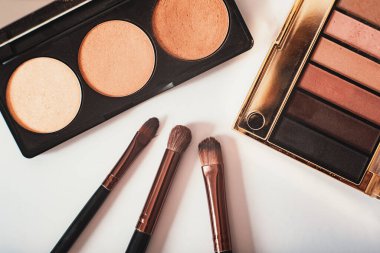 Dekoratif kozmetik ürünler, göz falı paletleri ve beyaz arka planda yakın plan kozmetik fırça, üst görüş. Makro. Makyaj sanatçısı iş akışı. Güzellik konsepti