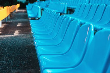 Stadyumdaki boş koltuklar. Mavi ve sarı sandalyeler, basit soyut bir spor şovunda kimse bulunmaz. Sandalyeler yakın, yan görünüm