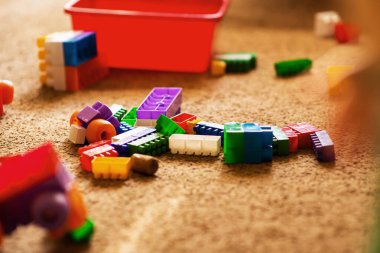 Çocukların plastik yapı taşları odanın zeminine saçılmış. Oda düzensiz bir halde. Rtx, mesaj yeri, mutlu çocukluk. Rahat atmosferi olan rahat bir ev. Çocuk gelişimi