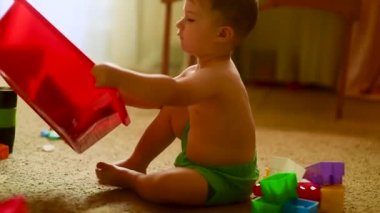 Küçük sevimli Avrupalı çocuk güneşli odada renkli inşaat setiyle oynuyor. Mutlu çocukluk konsantrasyonu. Rahat atmosferi olan rahat bir ev. Çocuk gelişimi, iyi motor beceriler