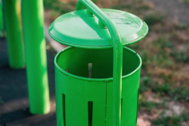 Parkta tatlı yeşil bir çöp tenekesi. Yeni, minimalist çöp kutusu. Çevresel koruma. Mesaj için yer var. Çöp öğütücüsünde sosyal sorunlar