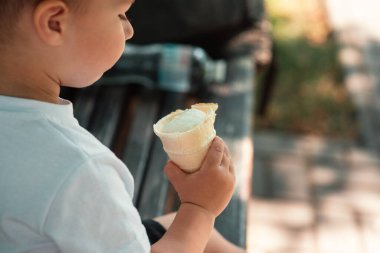 Küçük sevimli bir Avrupalı bebek dışarıda waffle bardağında dondurma külahı yiyor. Yakın plan. Yaz zamanı, sütlü tatlı, mutlu bir çocukluk. Duygular mutluluk. Çocukların neşesi