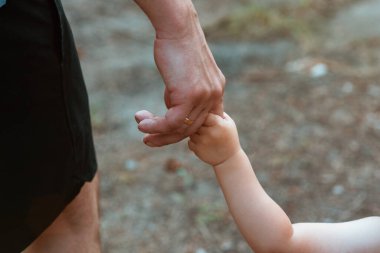 Babası küçük oğlunun elini tutuyor. Yakın plan. Bir babanın sevgisi ve bakımı. Babasıyla ormanda bir yürüyüş. Babalar Günü. Babalık. Film tarzında güzel sanatsal fotoğraf işleme