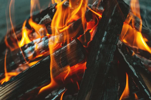 stock image A bright flame of fire over a campfire. Wooden wood stacked in a pyramid is burning. The flame of fire close-up. White smoke rises over the fire. Barbecue bonfire. Tourist concept