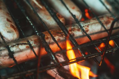 Barbekü ızgarasında süt sosisleri ateşte kızartılır. Ateşin alevlerinde sosisler kapımızda. Lezzetli ızgara sosis. Yaz tatili. Barbekü