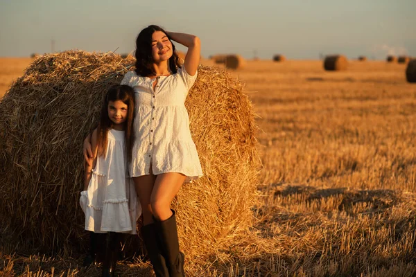 可爱的欧洲小女孩在日落时紧紧地拥抱着她的母亲 在一片修剪过的麦田和干草丛中 幸福的童年 — 图库照片