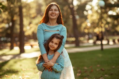 Anne ve kızı gün batımında. Parkta sonbahar yürüyüşü. Mutlu çocukluk ve annelik. Anne sevgisi. Yüksek kalite fotoğraf