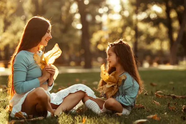 Мати Дочка Сидять Траві Парку Жовтим Листям Руках Заході Сонця — стокове фото