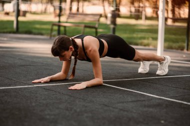 Genç bir bayan antrenör fitness sıkıştırma egzersizi yapıyor. Kız dışarıda antrenman yapıyor. Sağlıklı bir yaşam tarzı. Yüksek kalite fotoğraf