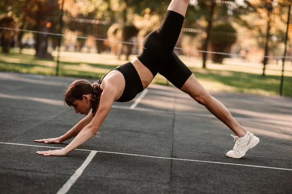 stock image A young female trainer performs a fitness compression exercise. The girl is working out outdoors. Healthy lifestyle. High quality photo